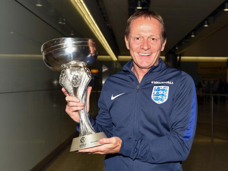 Keith Downing, der Trainer von Englands U19-Fußball-Nationalmannschaft zeigt den Pokal auf dem Flughafen Heathrow in London Keith Downing, der Trainer von Englands U19-Fußball-Nationalmannschaft zeigt den Pokal auf dem Flughafen Heathrow in London