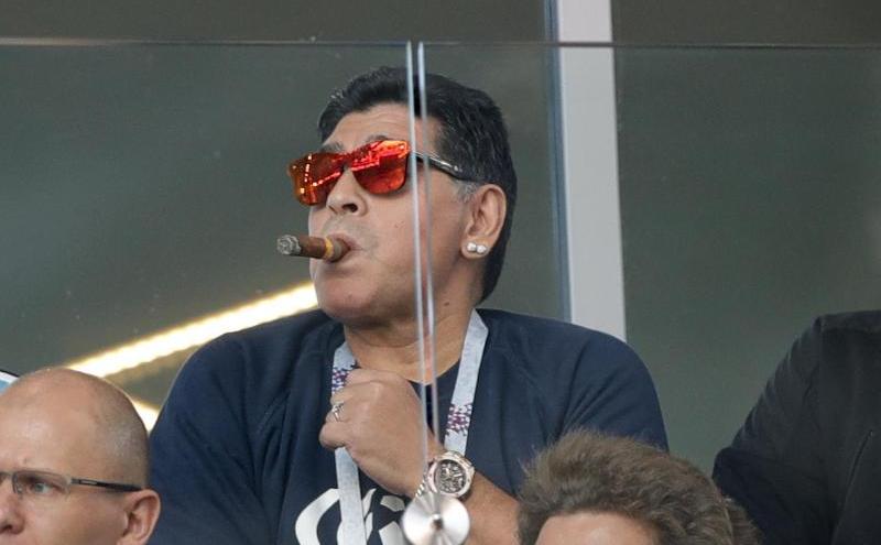 Brillies im Ohr, Zigarre im Mund: Fußball-Legende Diego Maradona sitzt beim Auftaktspiel Argentiniens mit Zigarre auf der Tribüne